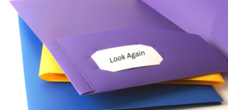 a stack of two-pocket folders with one open on top showing the inside label "Look Again" for positive corrections for student schoolwork - Watson Institute
