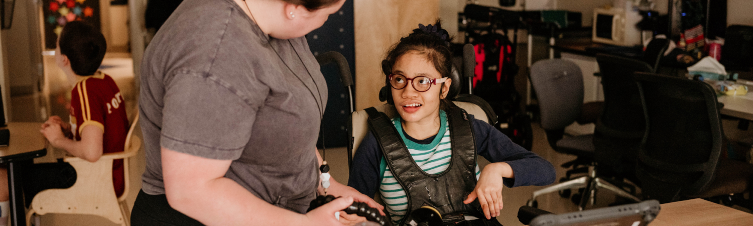 student with disabilities smiling at her teacher in classroom