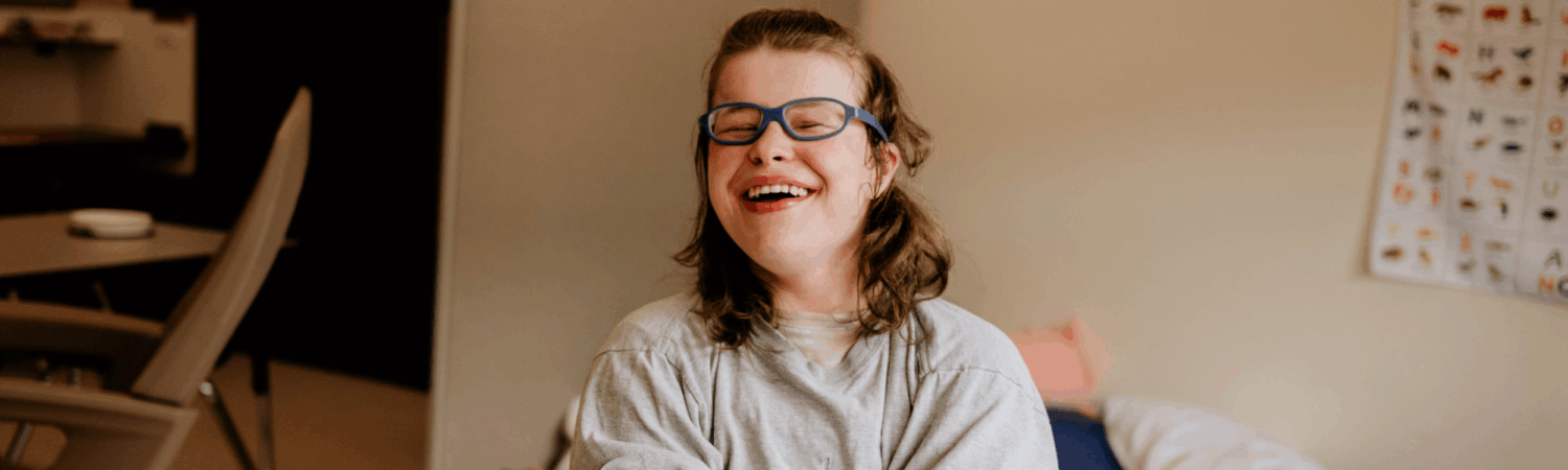 student with special needs laughing and smiling in her classroom - Watson Institute