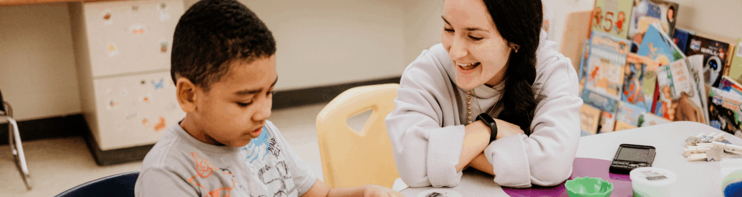 special education teacher helping young student with behavioral challenges in the classroom - Watson Institute