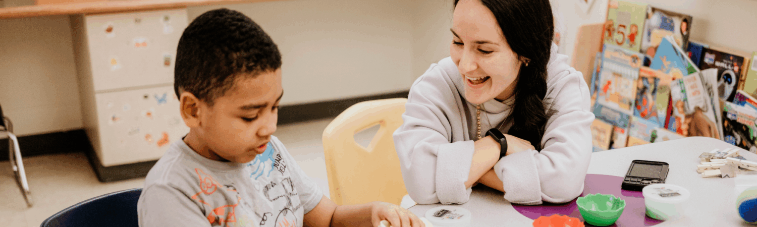 special education teacher pictured helping young student with behavioral challenges in the classroom - Watson Institute