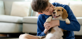 young boy shown cuddling a dog and showing kindness to an animal - Watson Institute