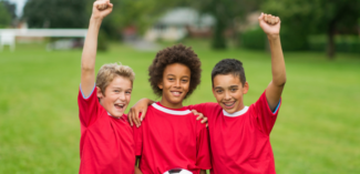 young boys encouraging each other on the soccer field - Watson Institute