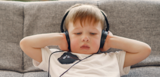 young child wearing headphones and relaxing in a calming space - Watson Institute