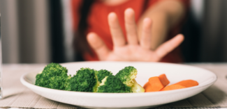 a picky eater pushes away a plate with nutritious vegetables - Watson Institute