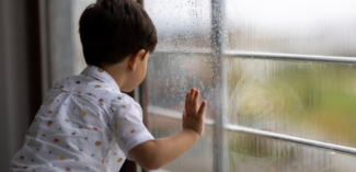student looking outside at the rain that changed outdoor recess on the schedule to indoor recess - Watson Institute