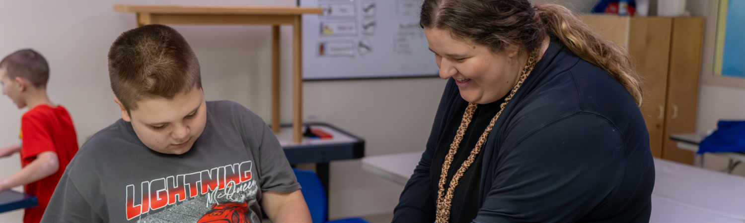 a special education paraprofessional is helping a student learn how to make food in the assisted living kitchen - Watson Institute
