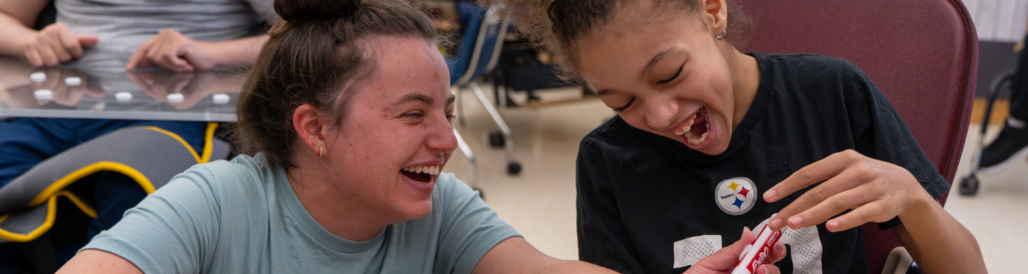 a special education teacher laughing in the classroom with a student with special needs - Watson Institute