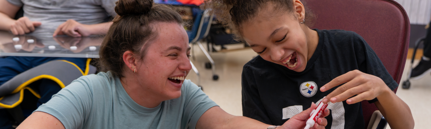 a special education teacher laughing in the classroom with a student with special needs - Watson Institute