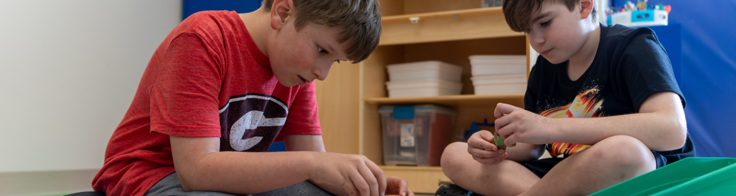 two young students are playing together in their classroom - Watson Institute