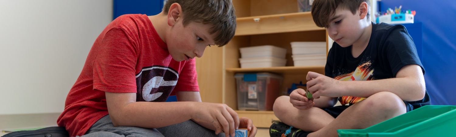 two young students are playing together in their classroom - Watson Institute