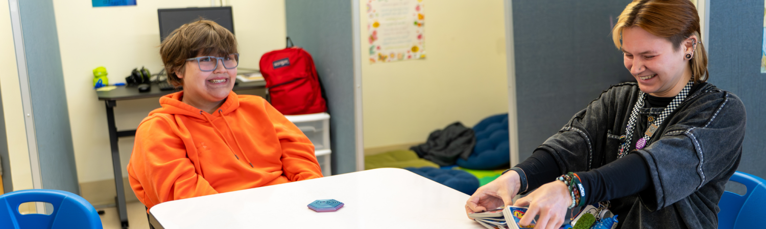 a behavior technician plays a card game with an autistic student in the WISCA program in the classroom - Watson Institute