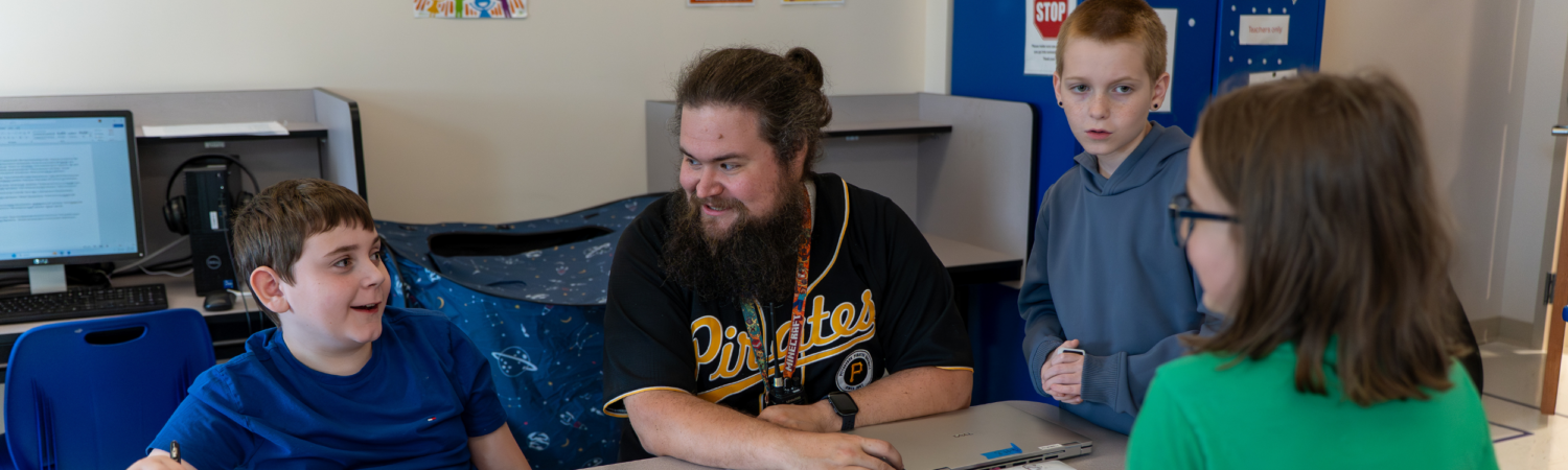 a special education teacher guides conversation with a group of students with autism in the classroom - Watson Institute