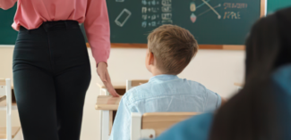 teacher stands in proximity to a student to refocus them on the classroom discussion - Watson Institute