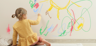 a young child is pictured drawing on walls - Watson Institute