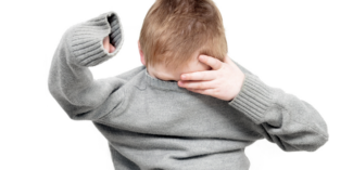 child putting on a sweater despite clothing challenges - Watson Institute