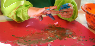 child is fingerpainting but a fellow student may have tactile defensiveness and need solutions to participate in another way - Watson Institute