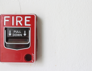 A red Fire alarm mounted on a wall is pictured to represent a fire drill.