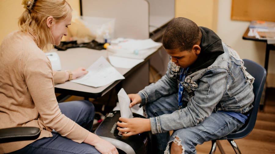 Behavior technician oversees a student shredding papers for their in-house vocational job.