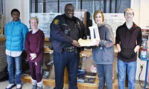 Students pictured with Police Officer holding a sweet potato pie