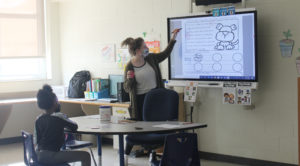 friendship academy student learning with teacher via a SmartBoard in the classroom
