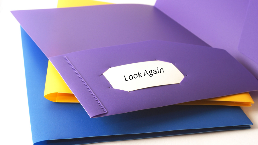 a stack of two-pocket folders with one open on top showing the inside label "Look Again" for positive corrections for student schoolwork - Watson Institute