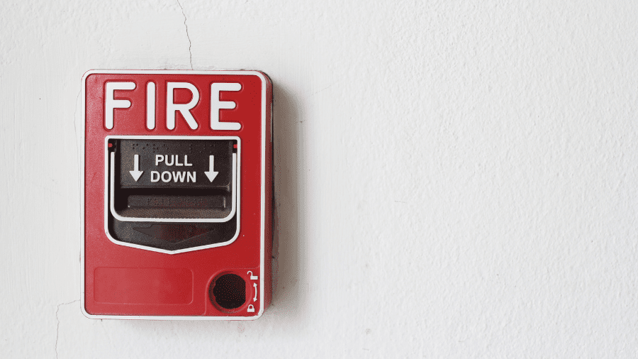 A red Fire alarm mounted on a wall is pictured to represent a fire drill.