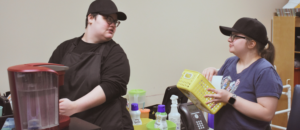Two Watson Institute students prepare coffee orders for their in-school jobs.