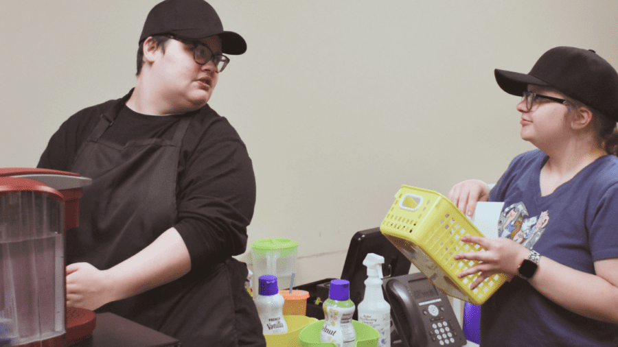 Two Watson Institute students prepare coffee orders for their in-school jobs.