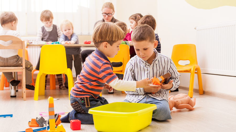 preschool-age students pictured playing together with other students playing nicely in the background in a classroom setting - Watson Institute