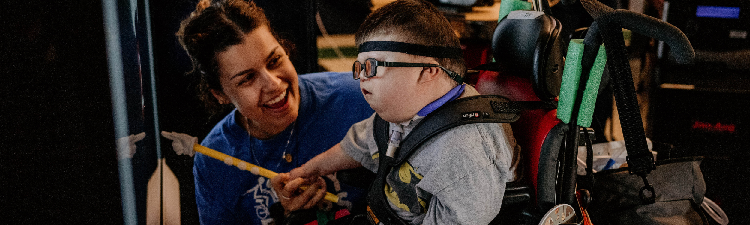 special education teacher helping young student with physical disabilities in the classroom - Watson Institute