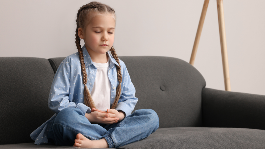 a young child is seated calmly with her eyes closed employing calming strategies - Watson Institute