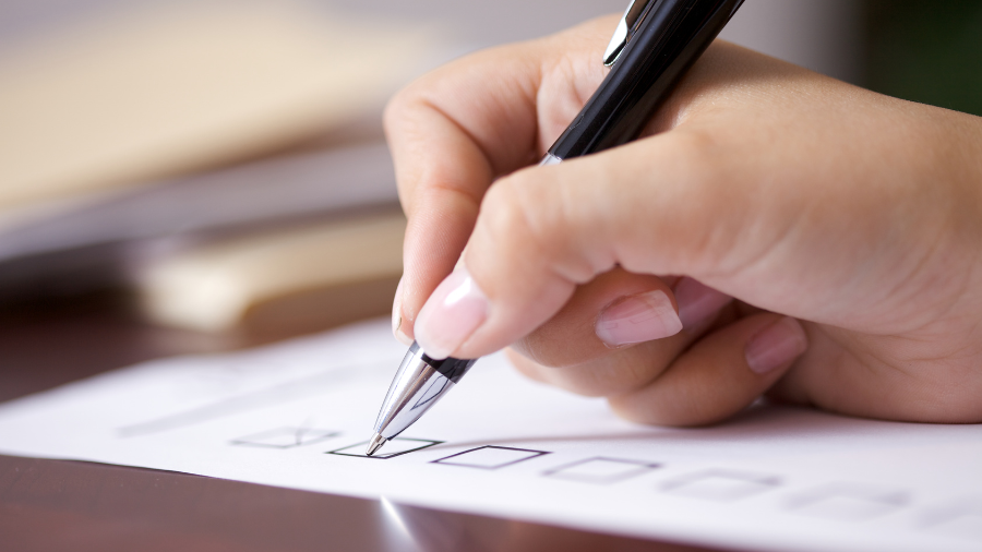 a hand is pictured checking things off of a positive behavior support plan checklist - Watson Institute
