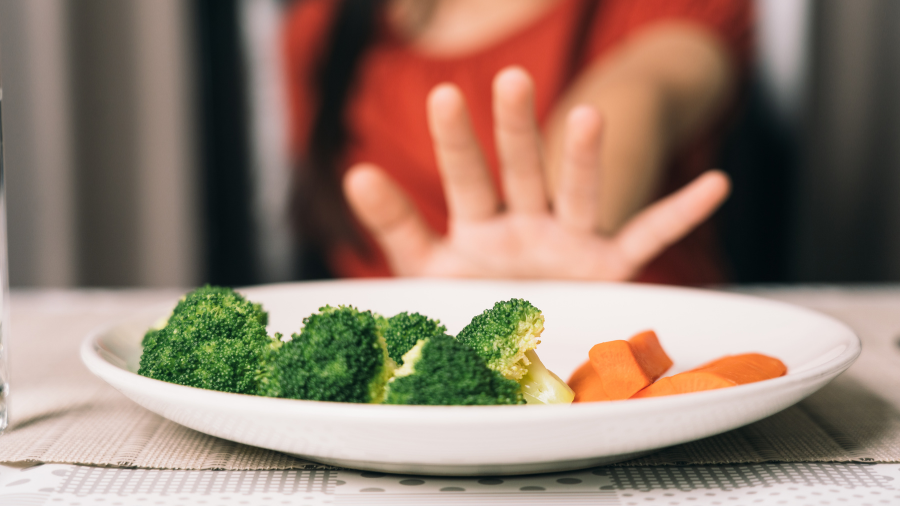 a picky eater pushes away a plate with nutritious vegetables - Watson Institute