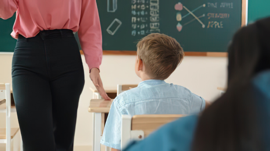teacher stands in proximity to a student to refocus them on the classroom discussion - Watson Institute