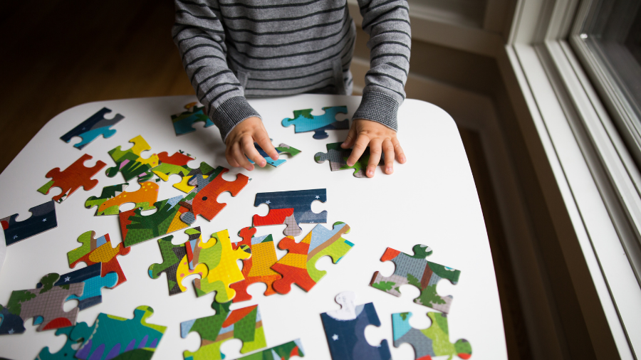 child learning problem-solving skills and persistence by playing with a puzzle - Watson Institute