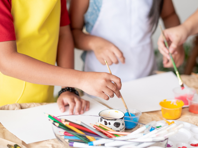 Students painting using paintbrushes and colored pencils to color as an alternative to fingerpainting due to tactile defensiveness - Watson Institute