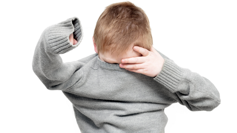 child putting on a sweater despite clothing challenges - Watson Institute