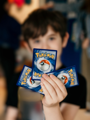 student holds up Pokemon cards indicating their special interest area (SIA) - Watson Institute